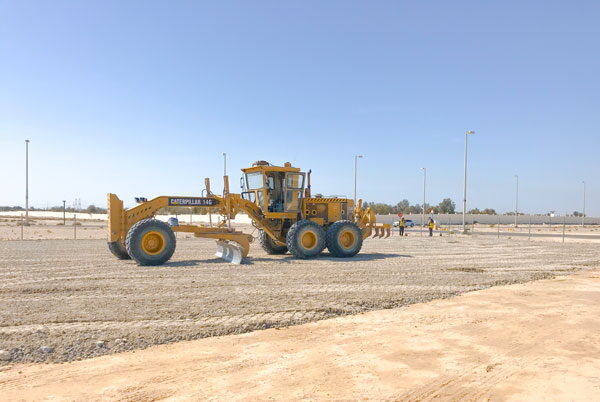 Motor grader levelling ground on an industrial plot